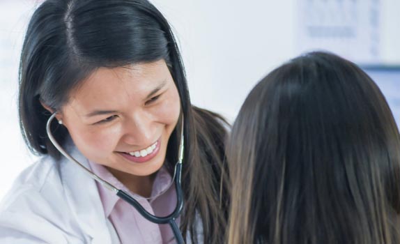 smiling doctor treating patient with stethoscope