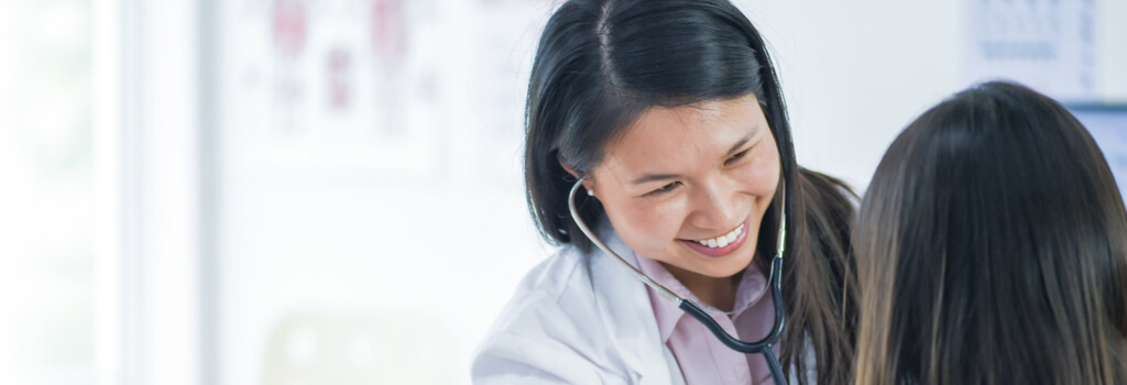 smiling doctor treating patient with stethoscope