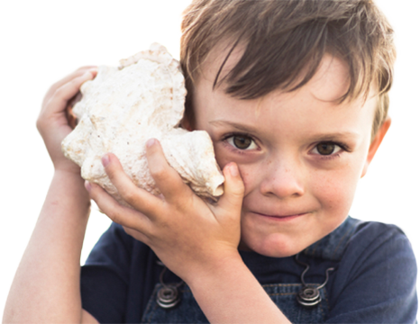 boy listening to sea shell
