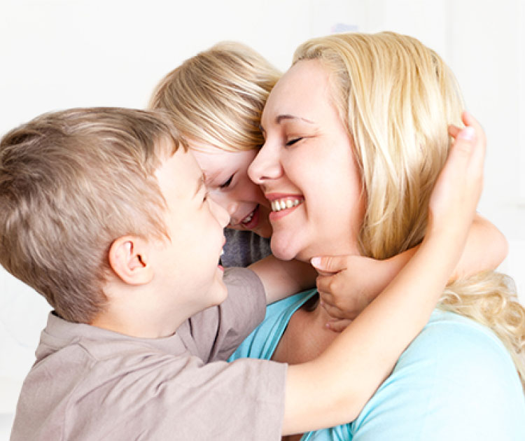 woman and two children embracing happily